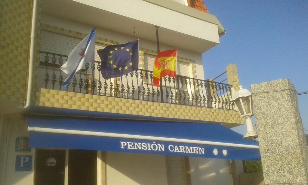 tres banderas volando en un balcón de un edificio en PENSION CARMEN **, en Sanxenxo