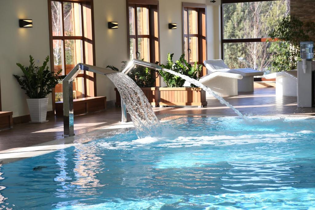 a water fountain in a swimming pool at Hotel Osada Karbówko Wellness & SPA in Elgiszewo