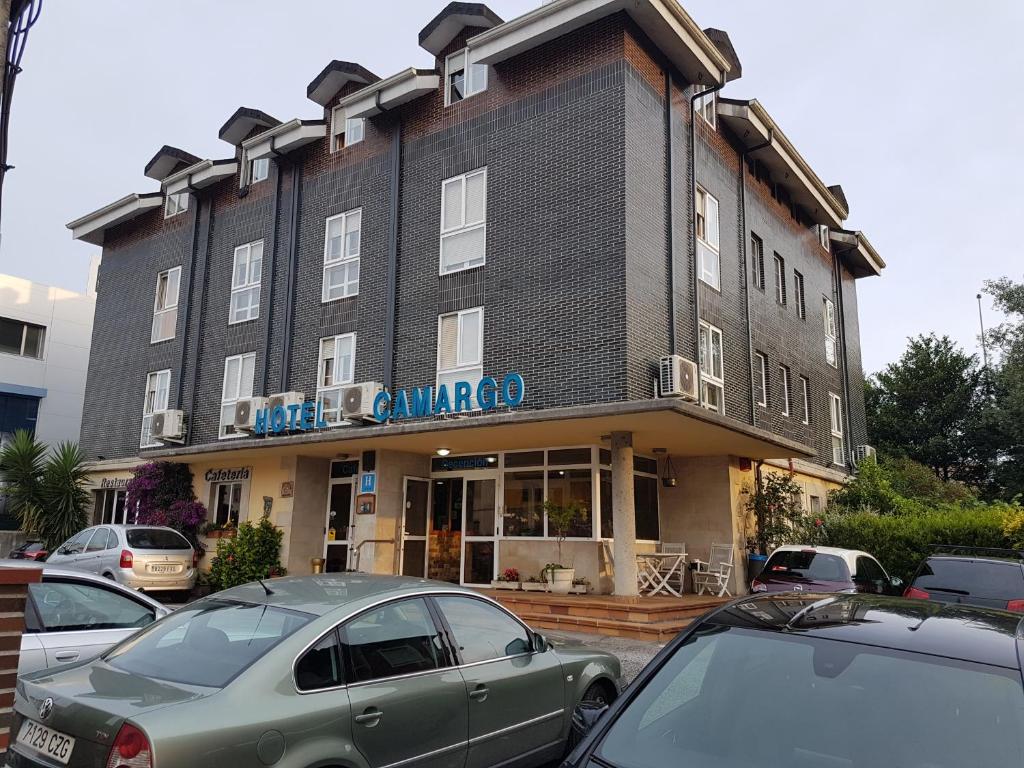 een groot gebouw met auto's geparkeerd voor het bij Hotel Camargo in Igollo