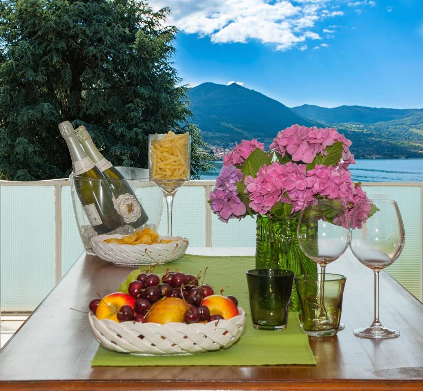 een tafel met twee manden fruit en bloemen en wijnglazen bij Casa Cristini in Marone