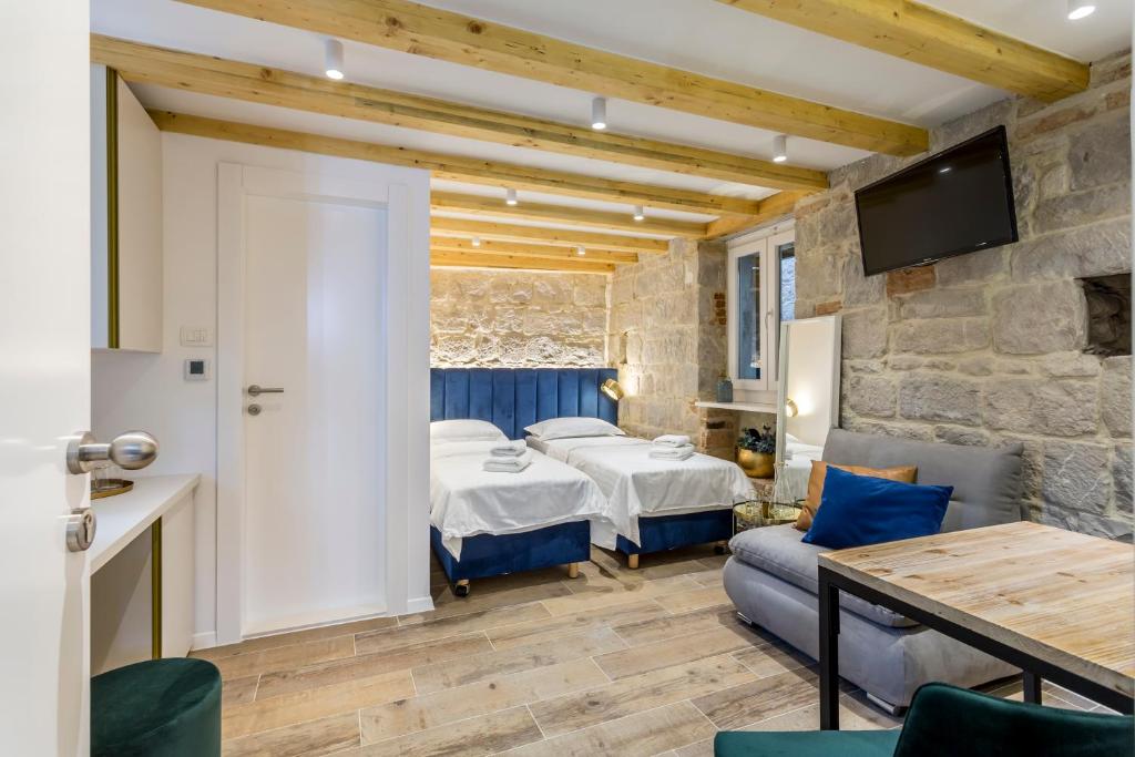 een slaapkamer met 2 bedden en een tafel en een bank bij Miara Luxury Rooms in Split