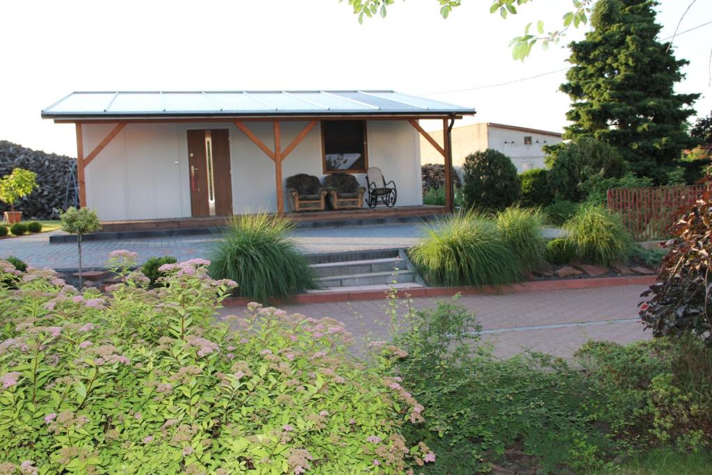 uma pequena casa branca com um alpendre com um banco em Agro Relax Nowodwór em Nowodwór