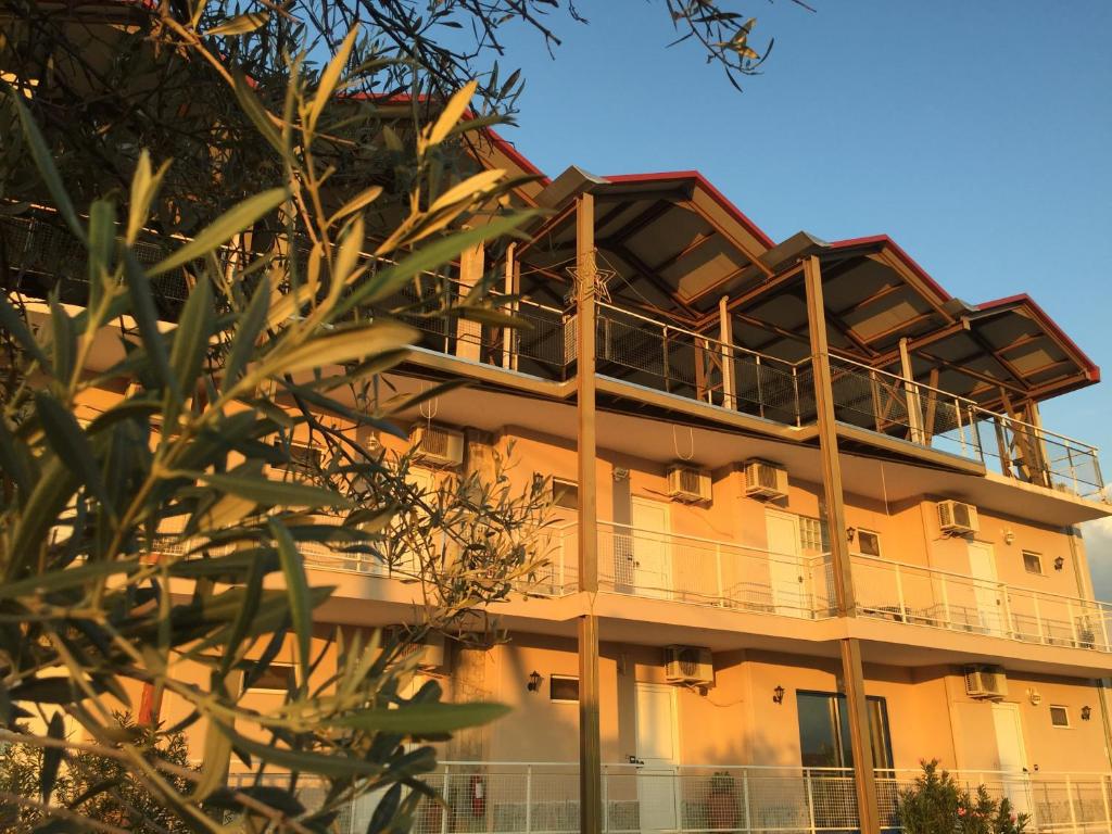 a building with a balcony on the side of it at Bay Holiday Hotel & Spa in Karavómilos