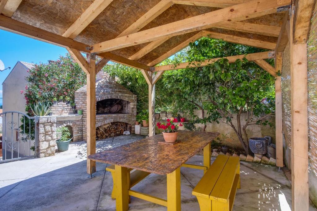a wooden pergola with a table and a fireplace at Apartments Ruka - free barbecue in Mali Lošinj