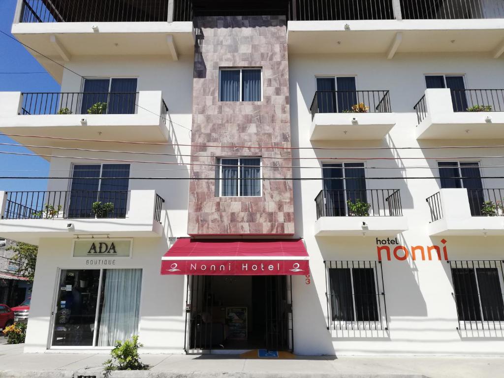 a tall white building with a red awning at Hotel Nonni in Santa Cruz Huatulco