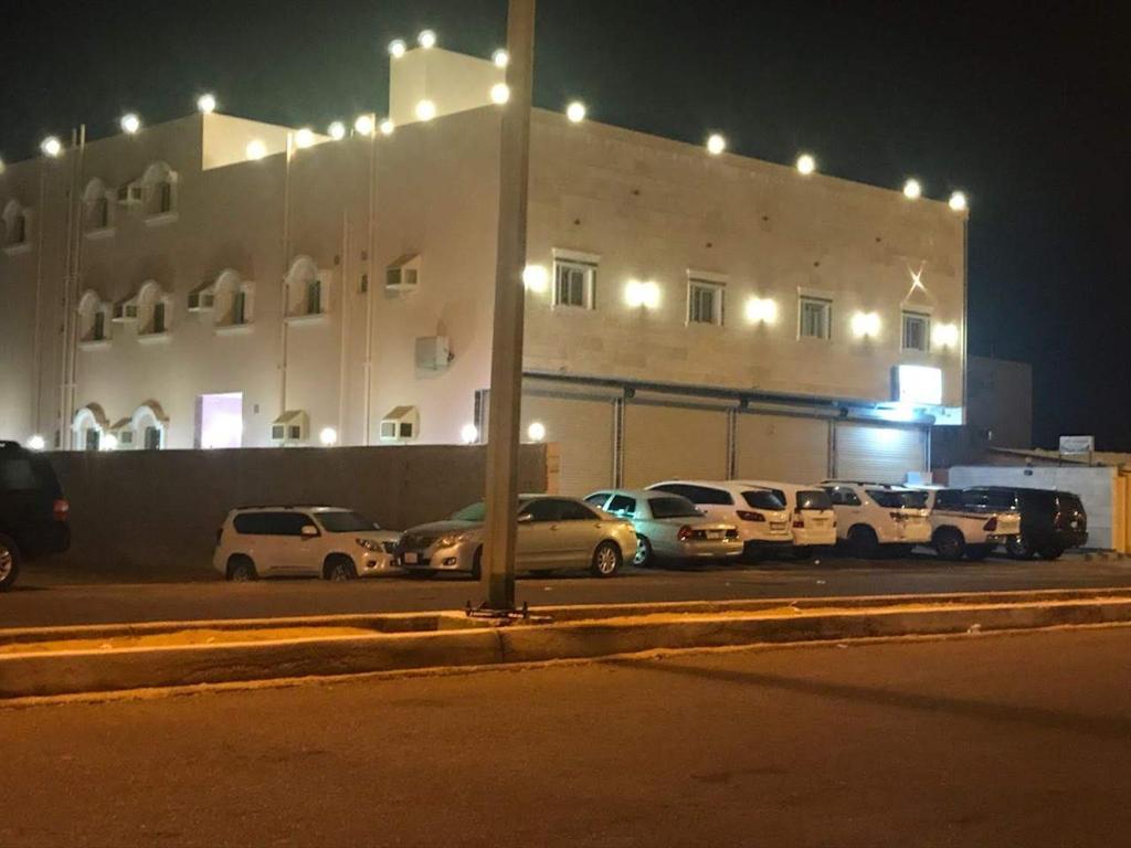 a parking lot in front of a building at night at Etlalet Al-Sharm Apartments in Yanbu