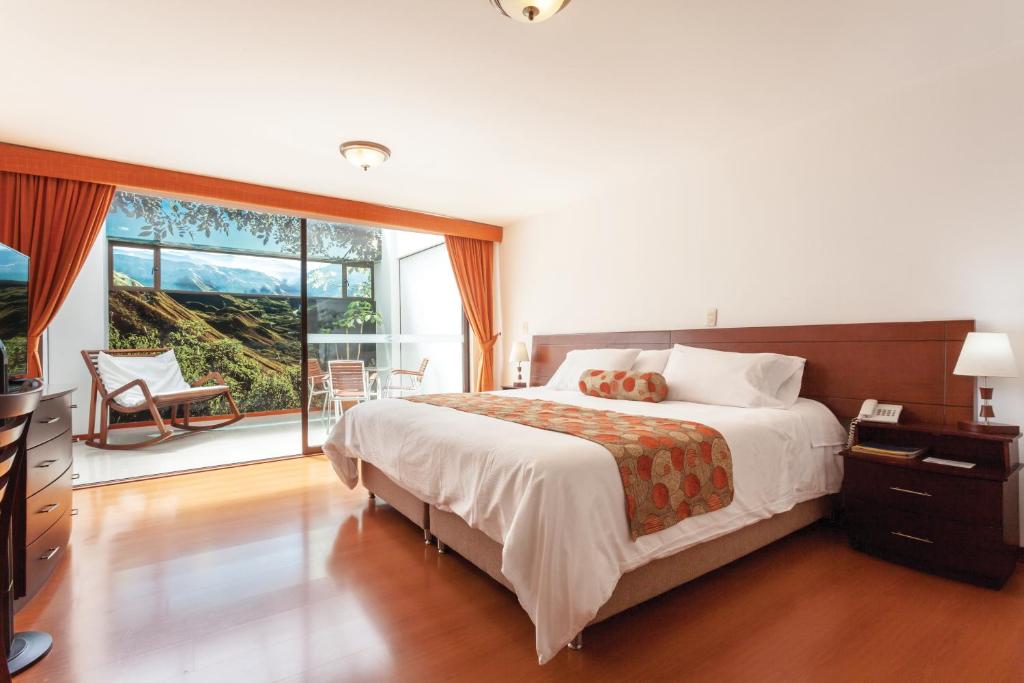 a bedroom with a large bed and a large window at Hotel Cuellars in Pasto