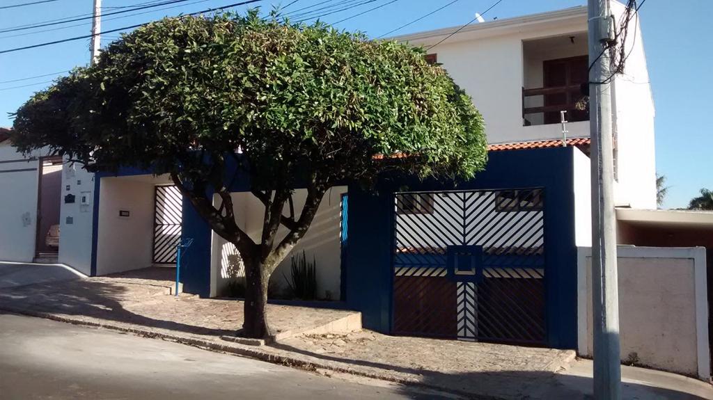 uma árvore em frente a uma cerca azul e branca em Pousada Parque Ecológico em Indaiatuba