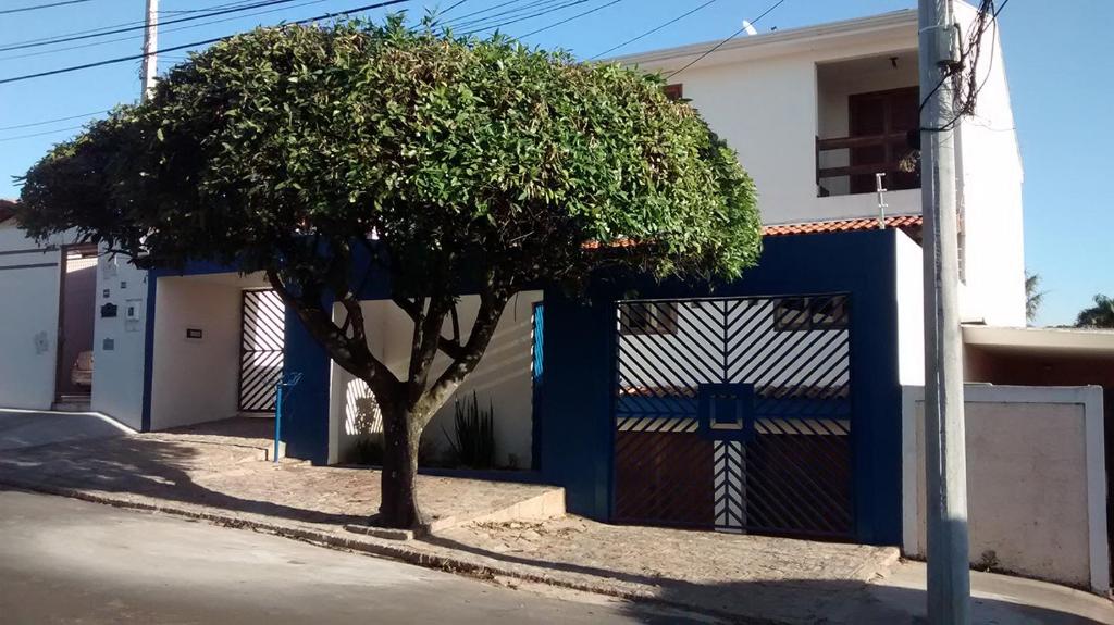 a tree in front of a blue and white fence at Pousada Parque Ecológico in Indaiatuba