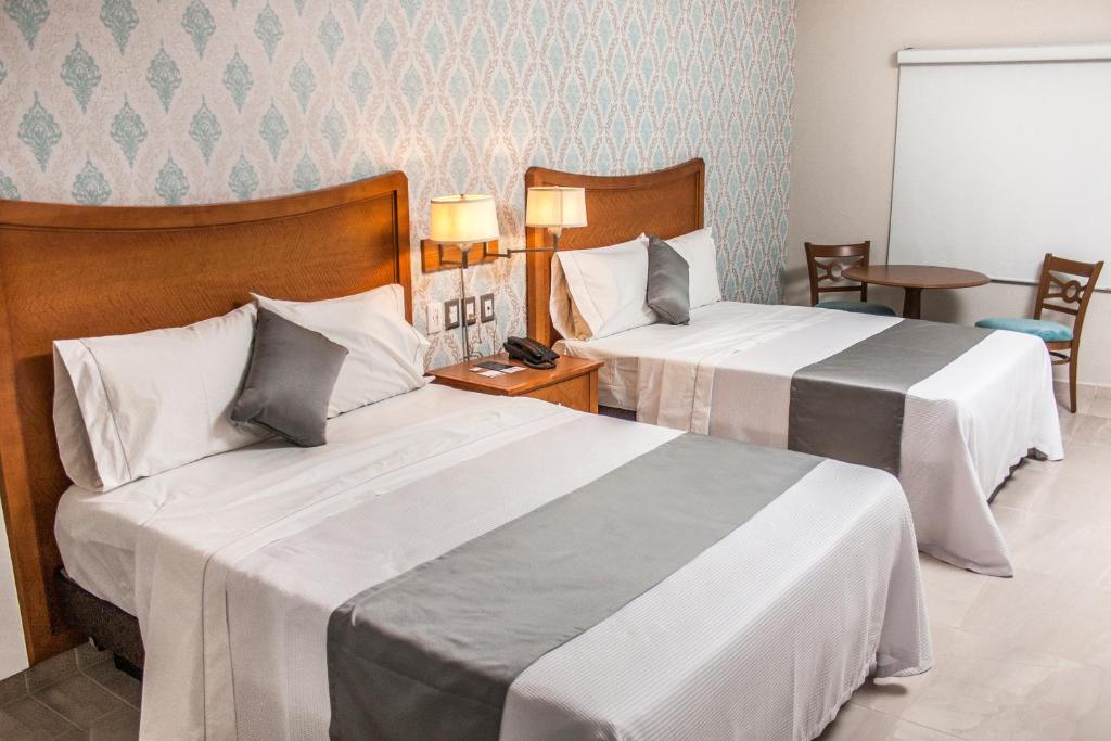 ein Hotelzimmer mit 2 Betten und einem Telefon in der Unterkunft Hotel Maioris Navolato in San Pedro