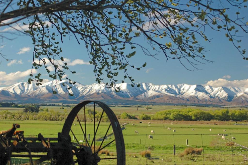 a view of snow covered mountains in a field with a wheel at Peter's Farm Lodge in Waipiata