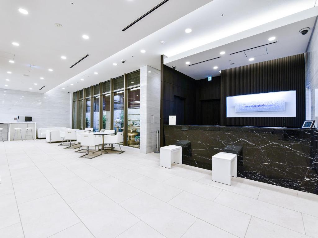 a lobby with a table and chairs and a screen at HOTEL UNIZO Osaka Shinsaibashi in Osaka