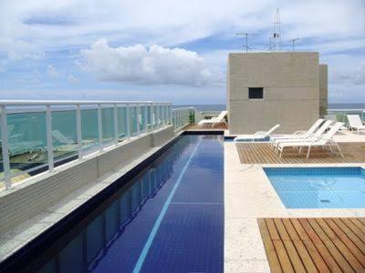 una piscina en la parte superior de un edificio con el océano en Condominio jtr brasil, en Maceió