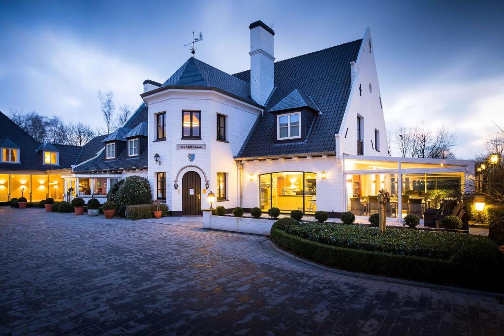 a large white house with a driveway at Hotel Restaurant Weinebrugge in Bruges