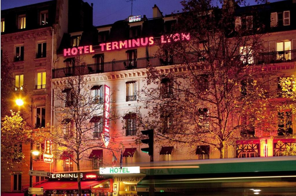 a building with a hotel transmitter inn lit up at night at Hotel Terminus Lyon in Paris