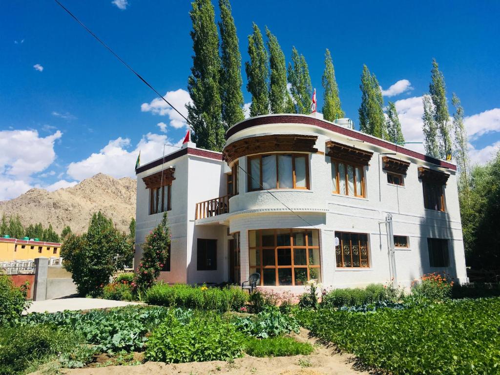 une grande maison blanche avec des arbres devant elle dans l'établissement PONYO stays, à Leh