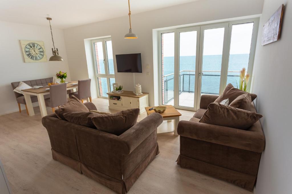a living room with two couches and a view of the ocean at Komfort-Ferienwohnung Waterkant by Meer-Ferienwohnungen in Olpenitz