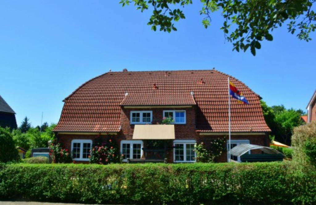 una casa marrón con techo rojo y bandera en Landjägerhaus am Südstrand - Wohnung 1 + 3 en Wyk auf Föhr