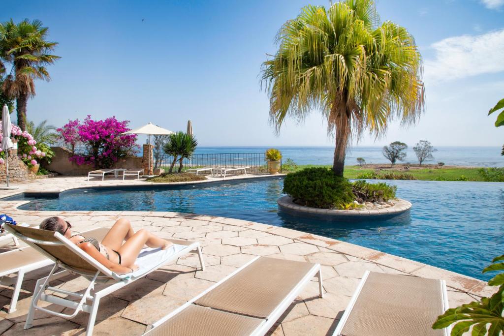 a woman laying in a chair next to a swimming pool at La Solenzara Hôtel in Sari Solenzara