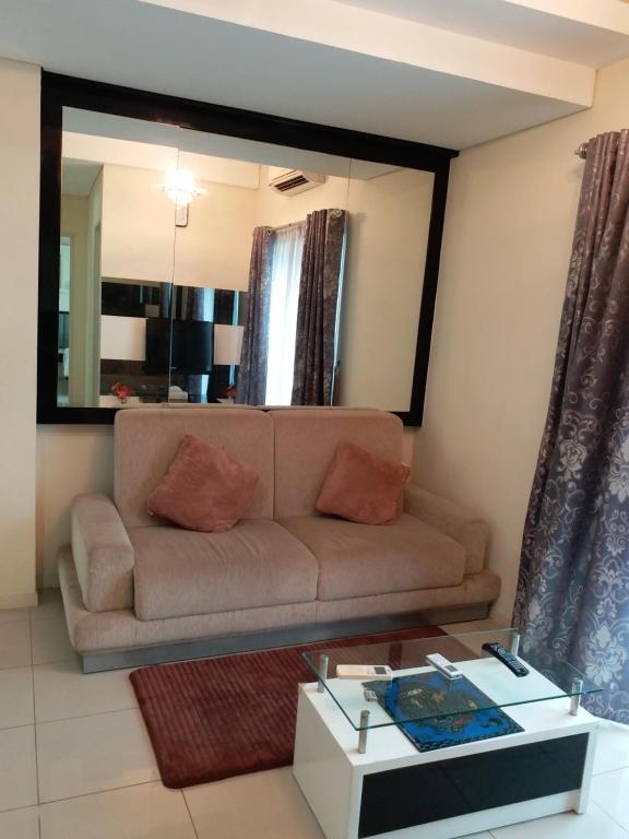 sala de estar con sofá y espejo en Apartment Cosmo Terrace, en Yakarta