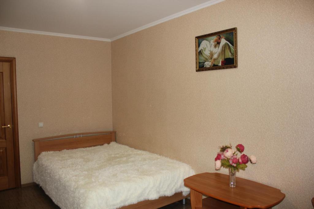 a bedroom with a bed and a vase of flowers on a table at Апартаменты на Пермякова in Tyumen
