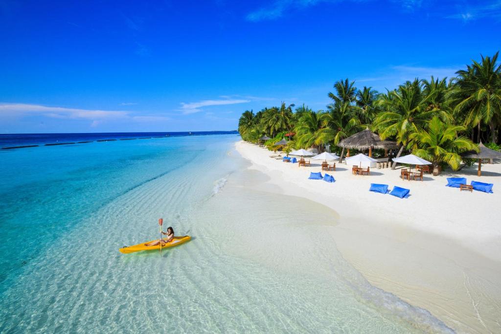 una persona en un kayak amarillo en una playa en Kurumba Maldives en Male