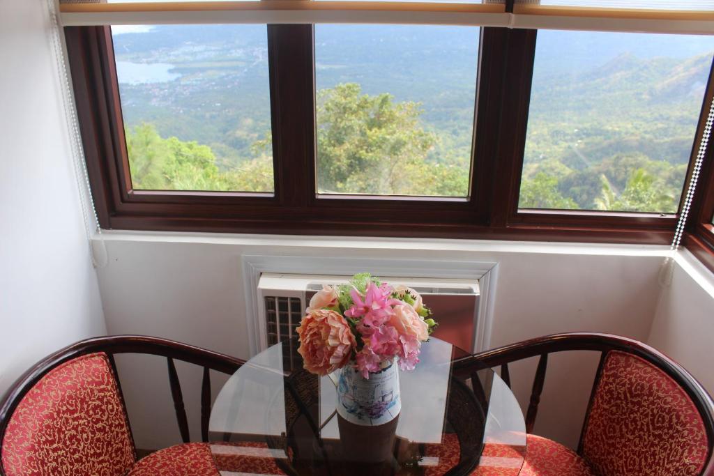a table with a vase of flowers on it with a window at Pura Vida Resort in Tagaytay