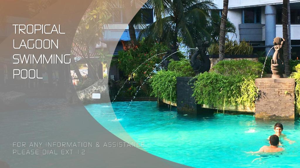 two people swimming in a swimming pool at a resort at Grand Tropic Suites Hotel in Jakarta