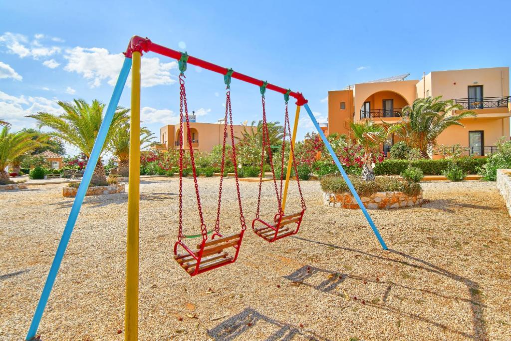 a swing in a playground with a building in the background at Nanakis Beach Apartments in Stavros