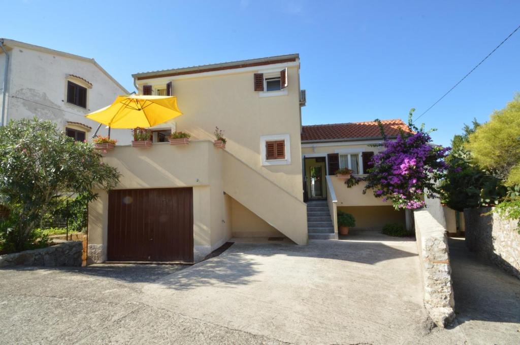 a house with a garage with a yellow umbrella at House Orhideja in Mali Lošinj
