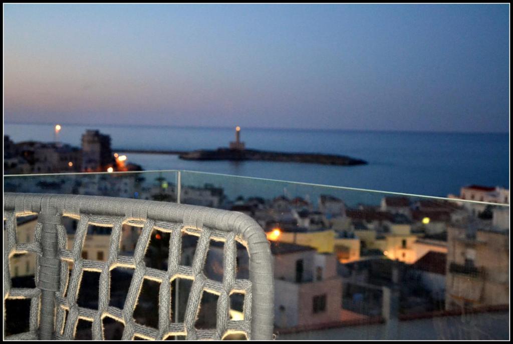 una silla blanca en la parte superior de un balcón con vistas al océano en Quintessenza - Charme Rooms en Vieste