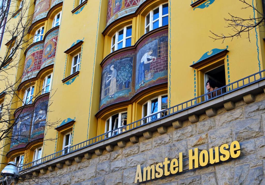 uma mulher a olhar pela janela de um edifício amarelo em Amstel House Hostel em Berlim