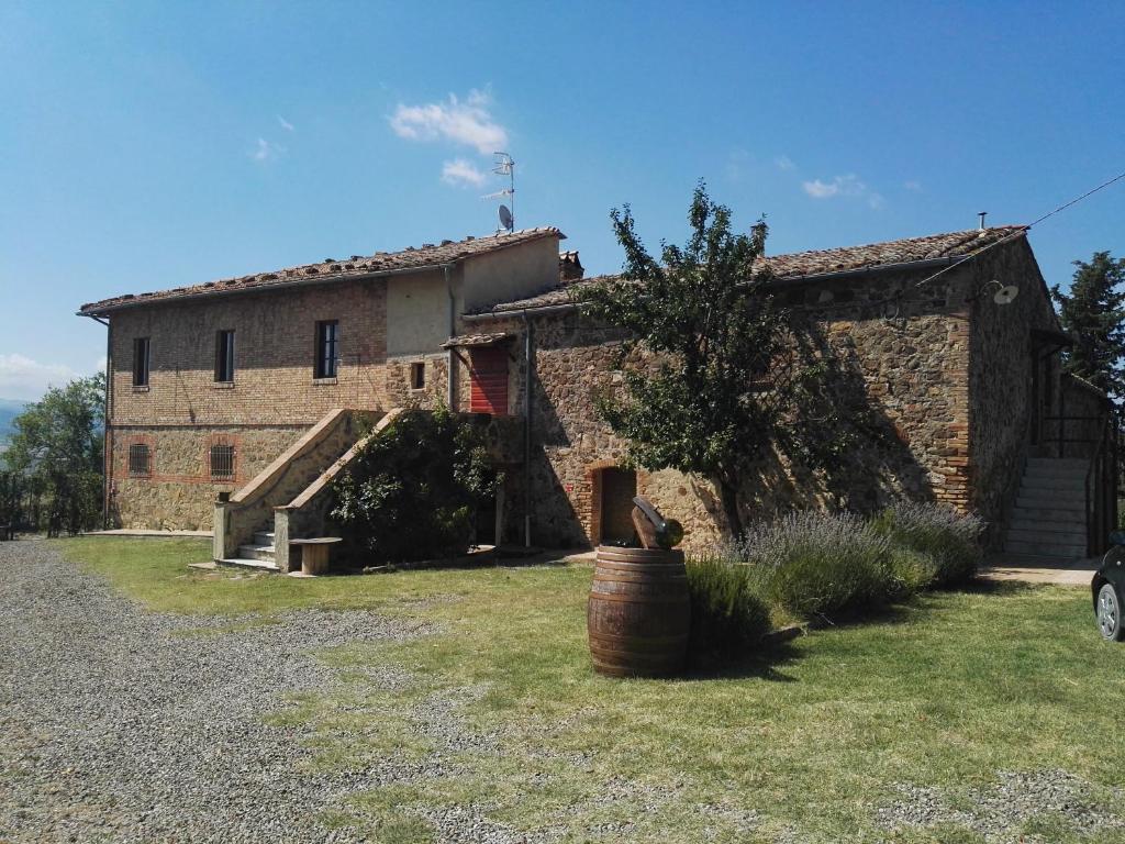 an old stone house with a barrel in front of it at Luce di Vino in Montalcino