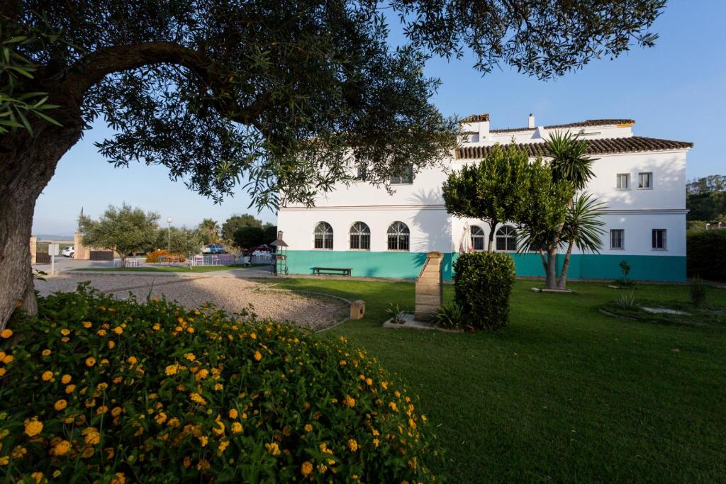 a white house with a tree and some flowers at Hotel Nómadas in Vejer de la Frontera