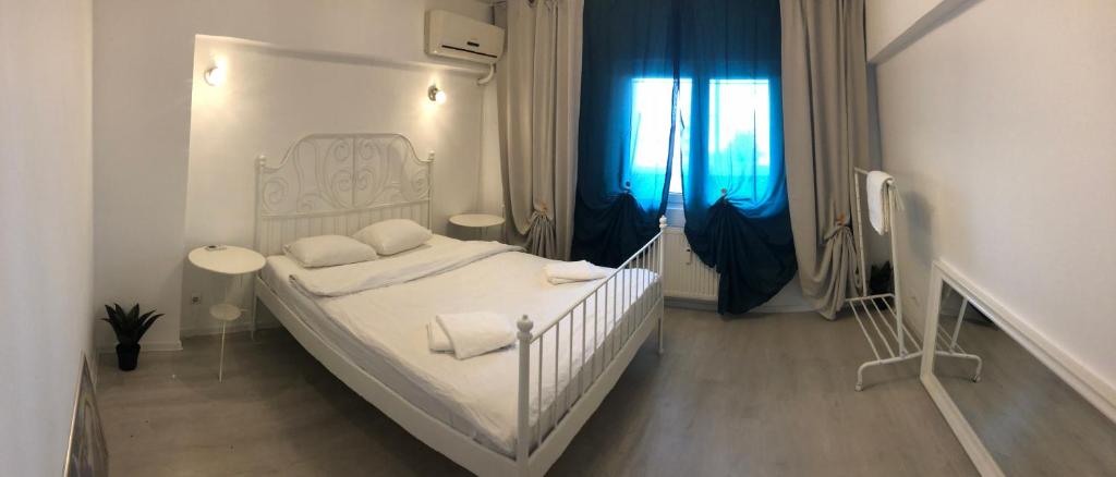 Green Apartment 59 في بوخارست: غرفة نوم بسرير ابيض وستائر زرقاء