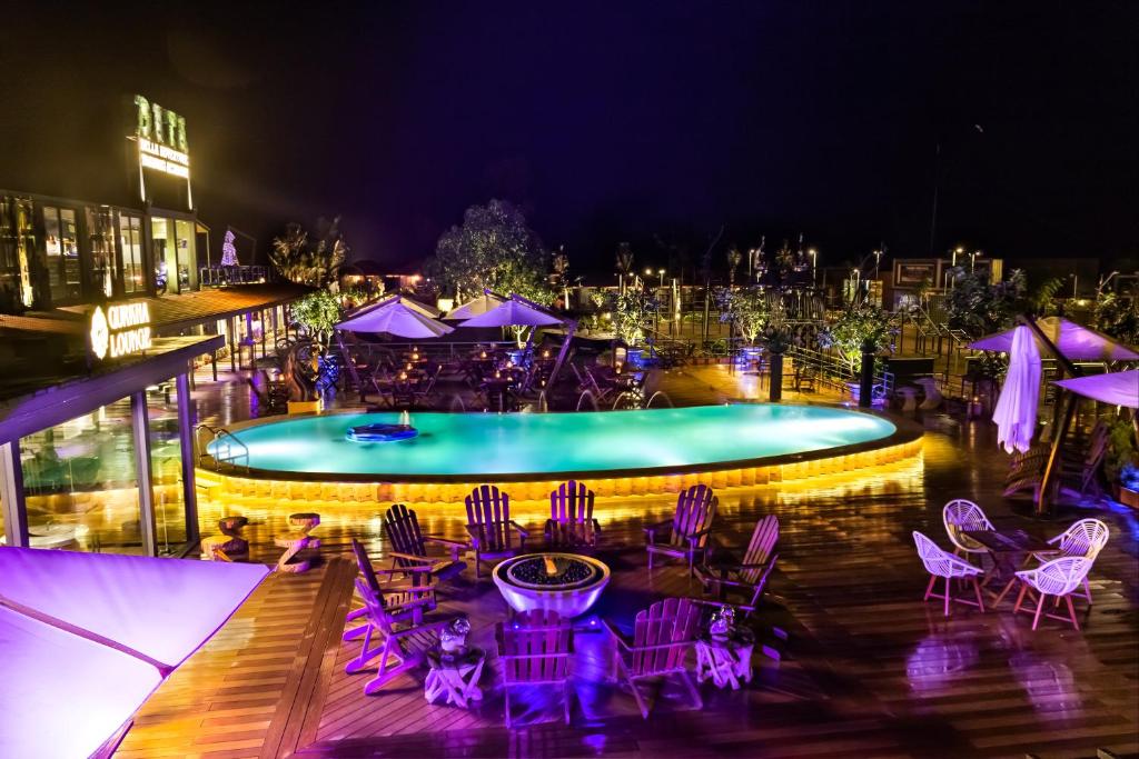 DATA Resort by Della Adventure في لونافالا: حمام سباحة مع الكراسي الأرجوانية والطاولات ومجموعة من المظلات