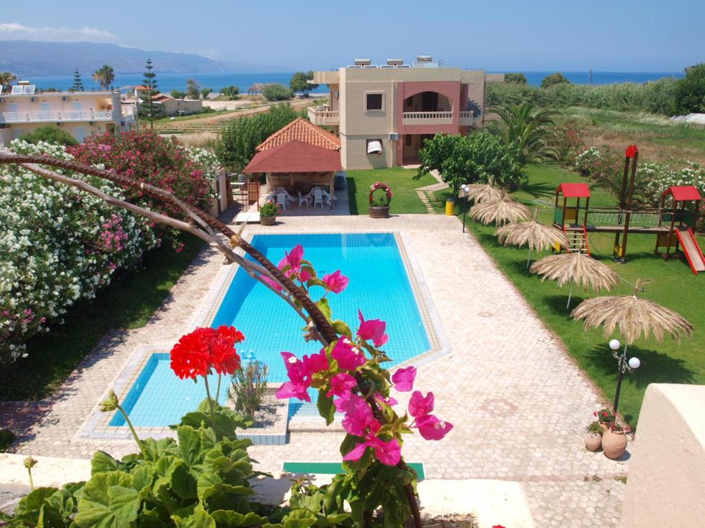 a swimming pool with flowers in front of a house at Villa Rita Apartments A in Tavronitis