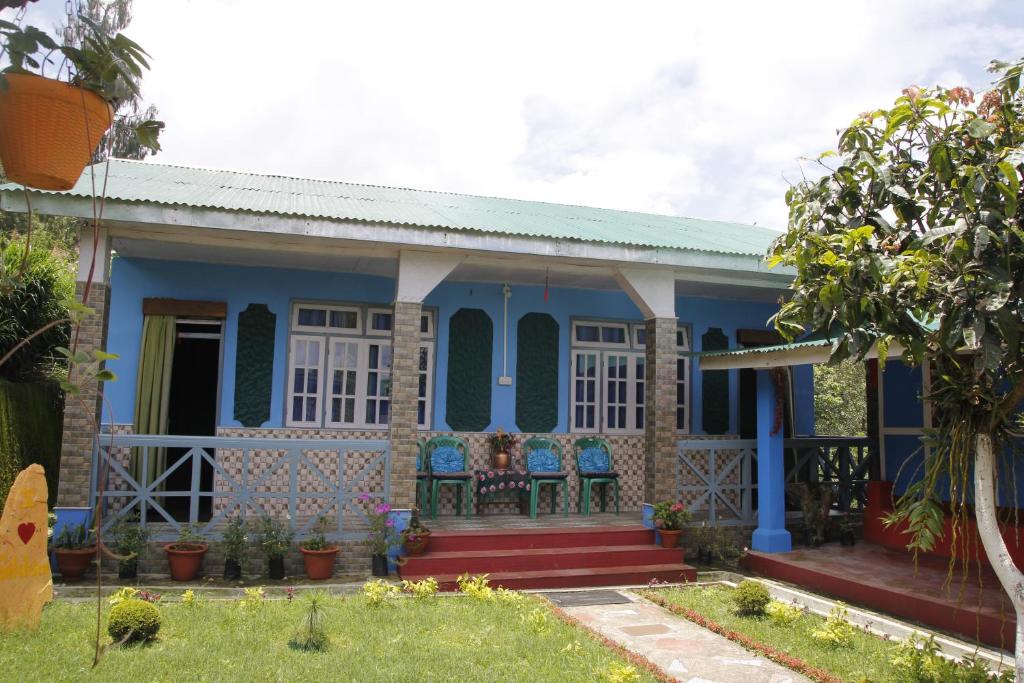 uma casa azul com cadeiras em frente em Vamoose Orchid Villa Homestay em Rinchingpong