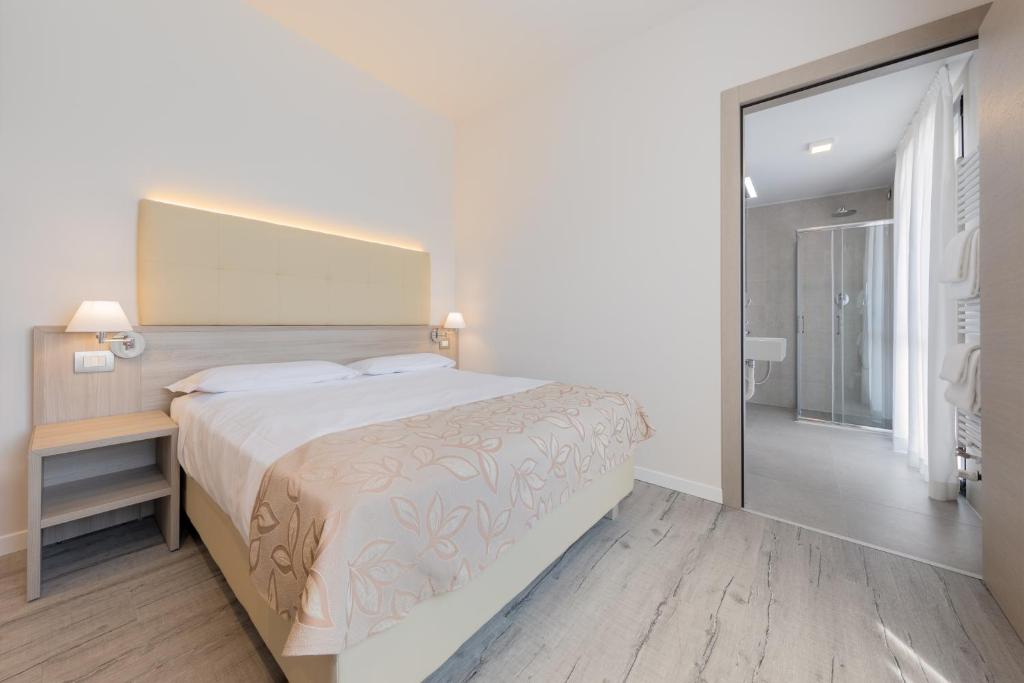 a white bedroom with a large bed and a mirror at Hotel Delfino Venezia Mestre in Mestre