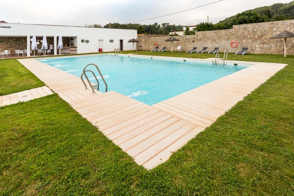 a swimming pool with a wooden walkway in the grass at Hotel Nómadas in Vejer de la Frontera