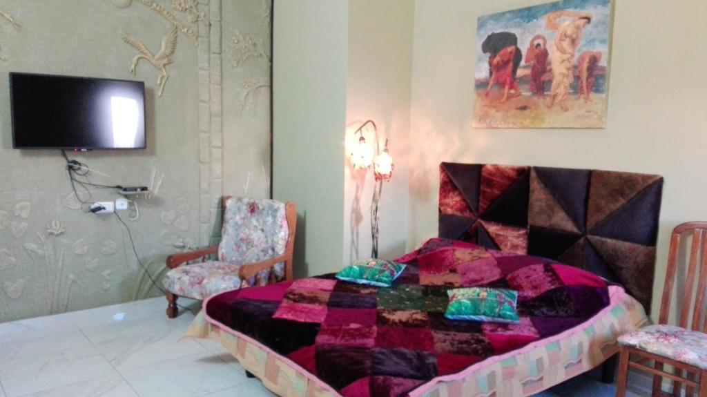 - une chambre avec un lit et une télévision murale dans l'établissement Domskazka, à Bruchim Qela' Alon