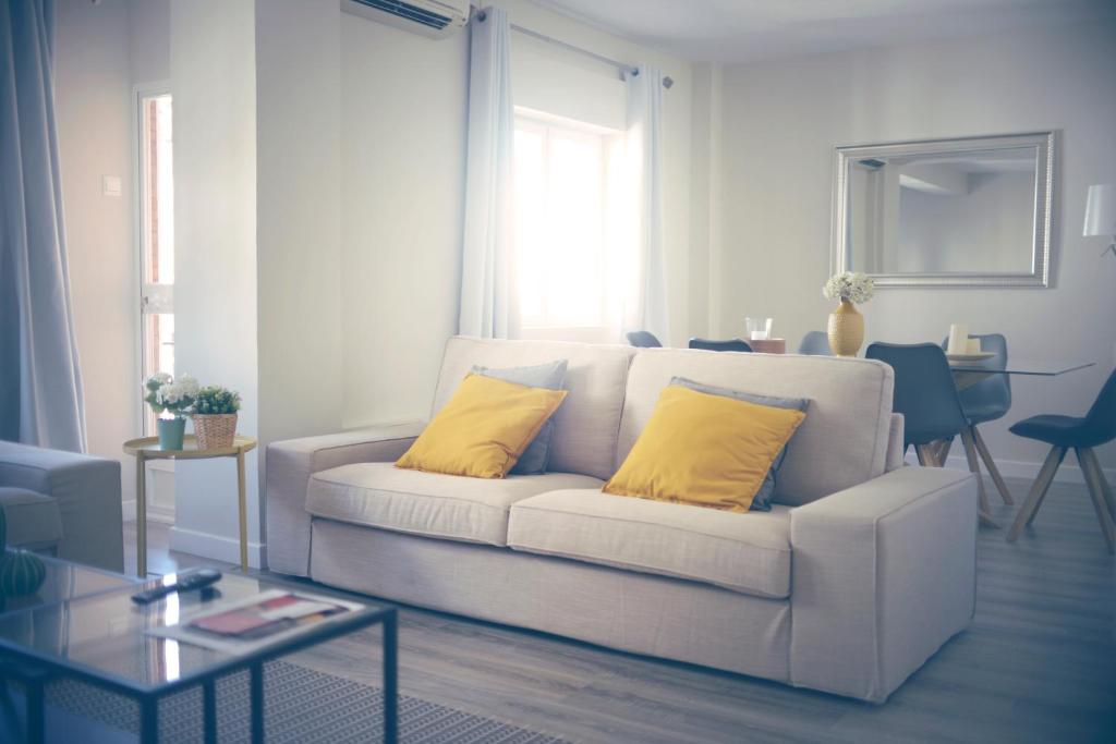 a living room with a white couch with two yellow pillows at Pinsapo (Centro ciudad) in Ronda