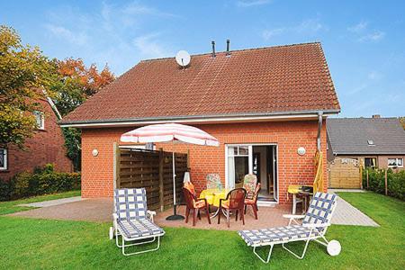 een huis met een tafel en stoelen en een paraplu bij Ferienhaus "Nico" in Dankern