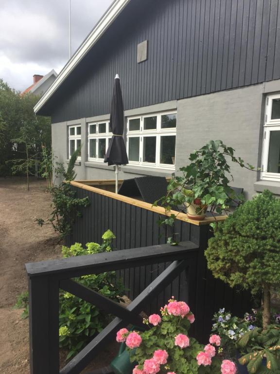 una casa negra con un paraguas y algunas flores en Molino en Bønnerup Strand