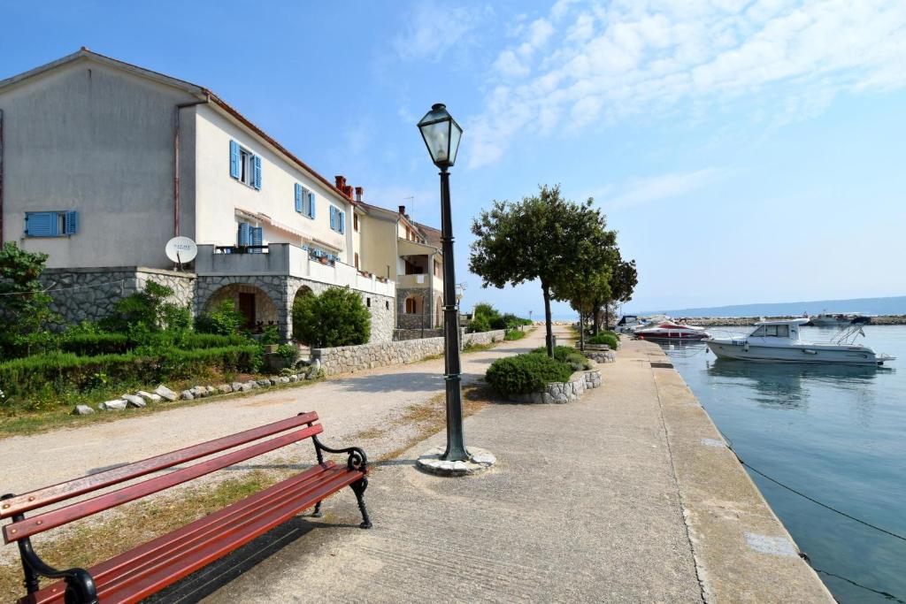 a red bench next to a light pole and water at Guest House Keti in Malinska