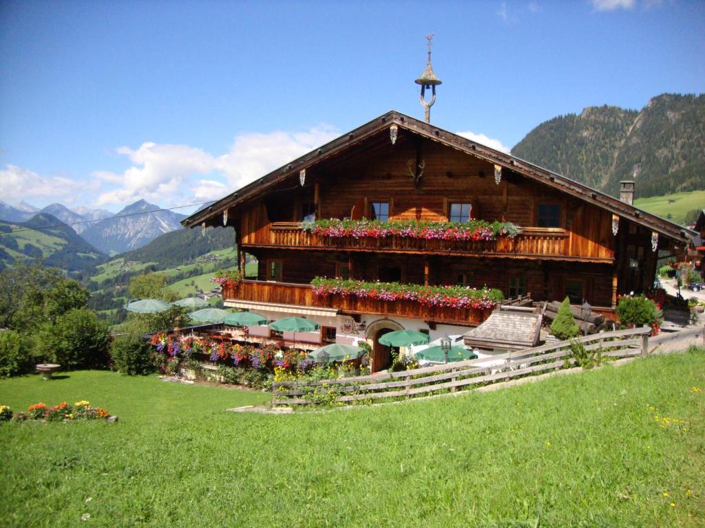 a building with flowers in front of it on a hill at Alpengasthof Rossmoos in Alpbach