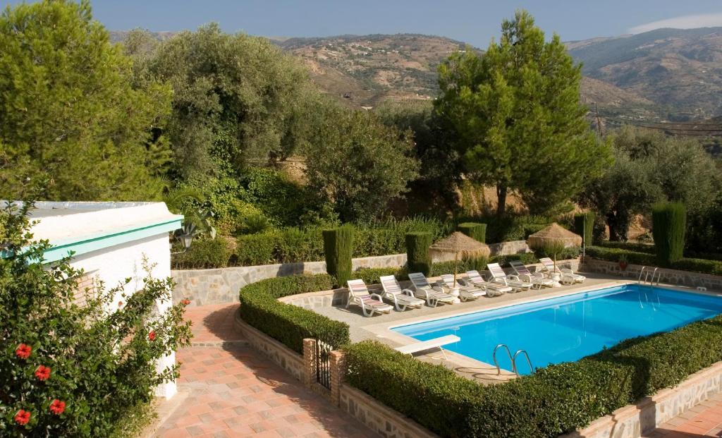 a swimming pool in a garden with lounge chairs at Cortijo Puerta Casas Rurales in Órgiva