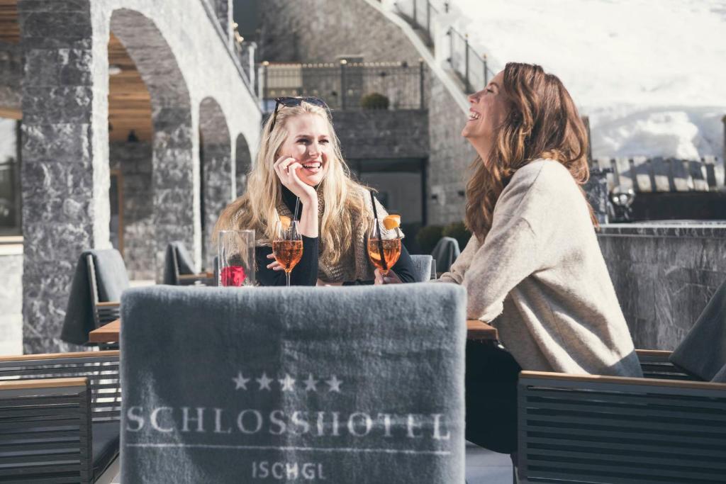 two women sitting at a table with glasses of wine at Schlosshotel Ischgl 5-Sterne Superior in Ischgl