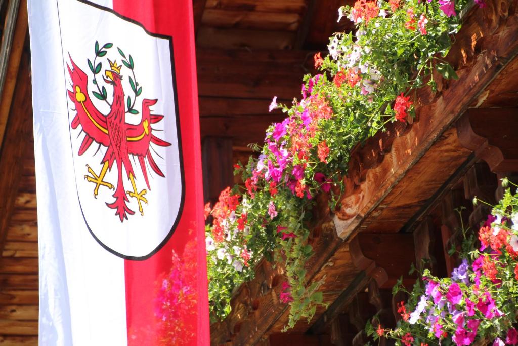 a flag and flowers next to a building at Appartements Moahof Zuhaus in Alpbach