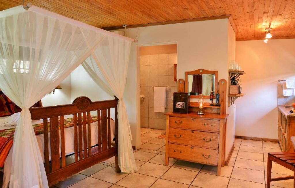 a bedroom with a canopy bed and a bathroom at Kasane Self Catering in Kasane
